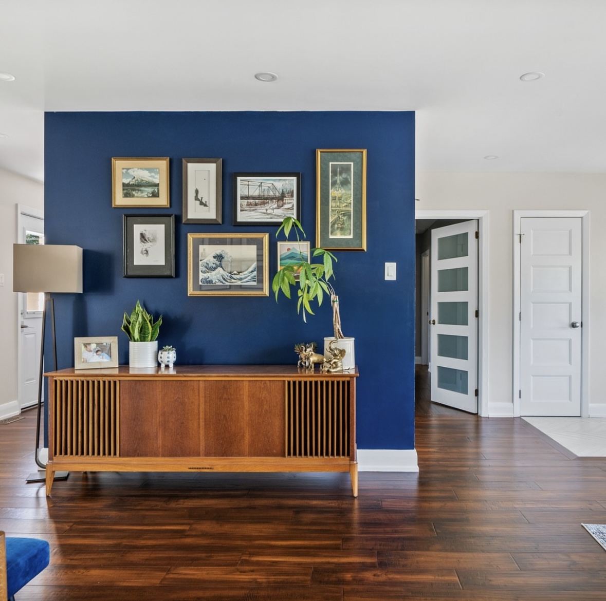 Dark blue accent wall covered in art.